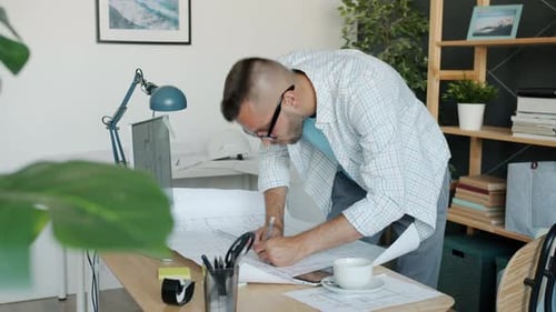 Portrait of Young Specialist Architect Working in Office Drawing on Construction Plan Looking at