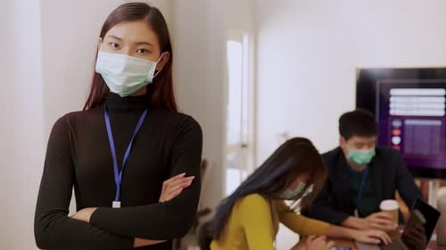 Young people with face masks back at work in office after lockdown.Asian small business startup