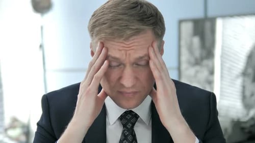 Stressed Man Massaging Temples in Office Close Up
