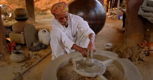 Potier professionnel qualifié lançant le volant du potier et façonnant un récipient en céramique traditionnel et