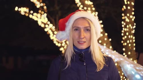 Woman in Santa Hat Smiling with Christmas Lights