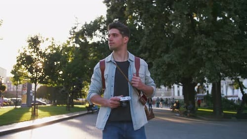 Attractive Young Handsome Man Tourist with Backpack Walking in City Center and Taking Photos on