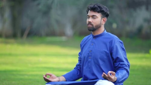Man Meditating Outdoors in Nature on Green Lawn