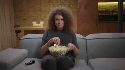 Woman Eats Popcorn Relaxing on Couch Indoors
