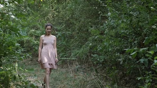 Girl in pink dress walks through the forest slow motion video