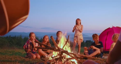 Children Gather Around Campfire Roasting Marshmallows at Sunset