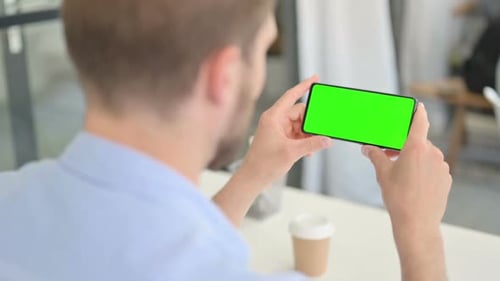 Man Holding Smartphone with Green Screen in Office