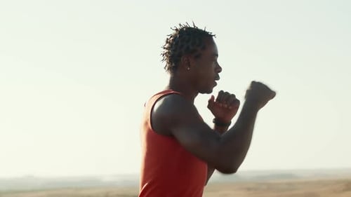 Black Boxer Runs and Trains His Punches Outdoors Background Sky Side View
