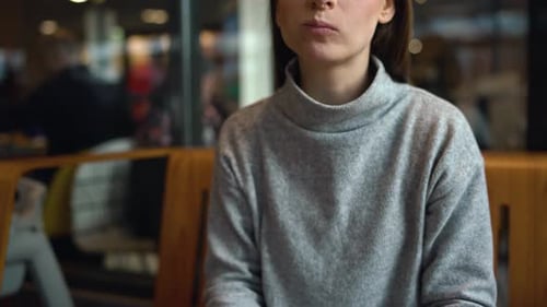 Woman Eats a Hamburger in a Cafe