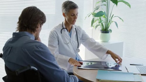 Doctor Explains X-Ray Results to Patient in Wheelchair
