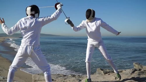 A man and woman fencing on the beach