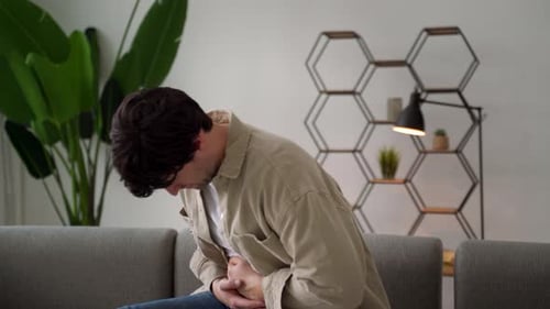 Man Suffering Stomachache Sitting on a Couch in the Living Room at Home