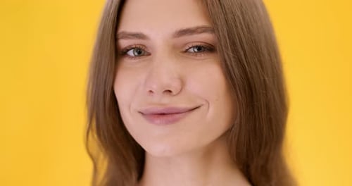 Woman Smiling and Winking on Yellow Background