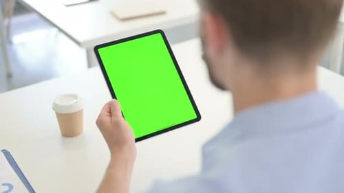 Man Using Tablet with Green Screen in Office