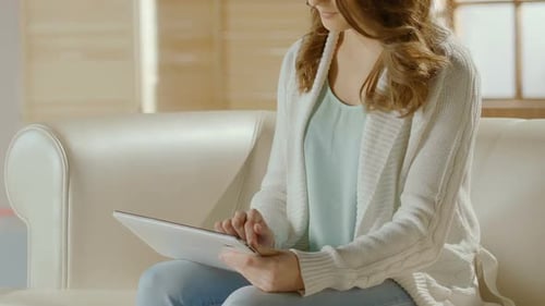 Woman Uses Tablet Device on Couch Indoors