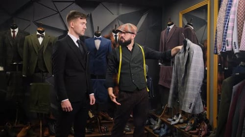 Mature Tailor Helps the Client Choose a Classic Three-piece Suit in an Atelier. Creative Adult