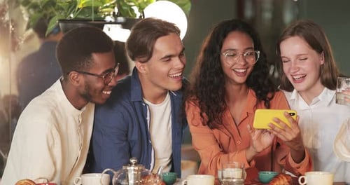 Friends Laughing Together Watching Phone in Cafe