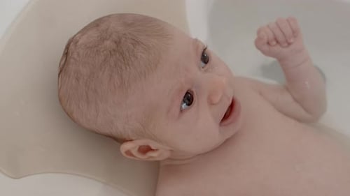 Infant lies in tub filled with water