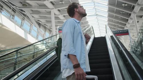 Male Tourist with Luggage Going Up the Escalator on Railway Station Indoors