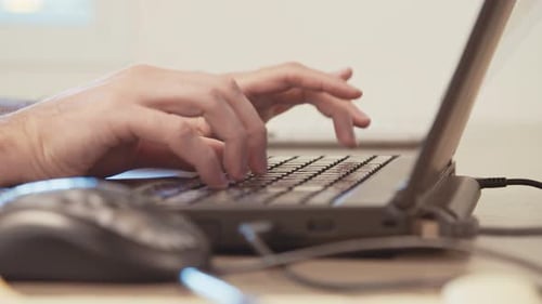 Man hands typing on a laptop computer keyboard