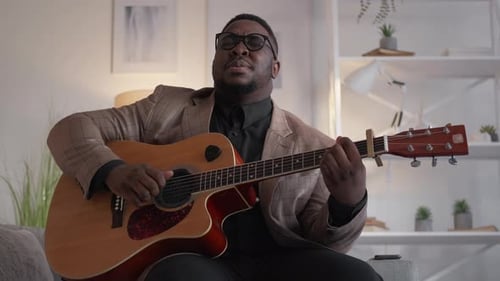 Man Playing Acoustic Guitar and Singing Indoors