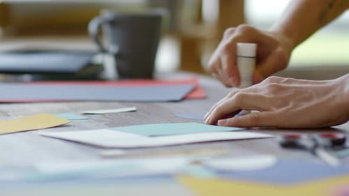 Close Up Hands Gluing Paper Cutouts on Table