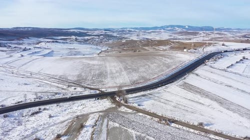 Fliegen über eine kurvenreiche Straße mit fahrenden Autos an einem frostigen sonnigen Wintertag