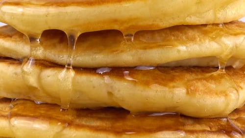 Pancakes with honey on a white background.