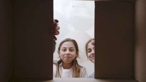 Young Parents with Daughter Unpacking Box with Happiness