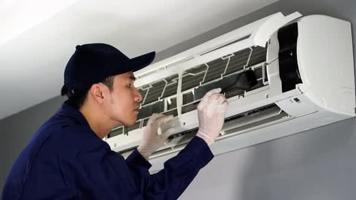 technician service using brush to cleaning the air conditioner indoors