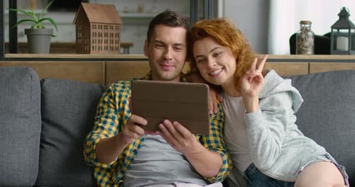 Couple Relaxing on Couch at Home with Tablet