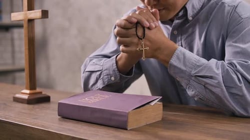 A young Christian man sitting in a church praying to God.