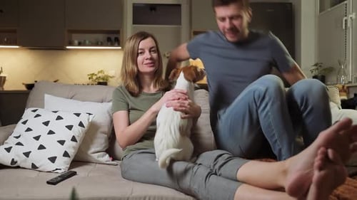 Couple Relaxing on Couch with Dog at Home