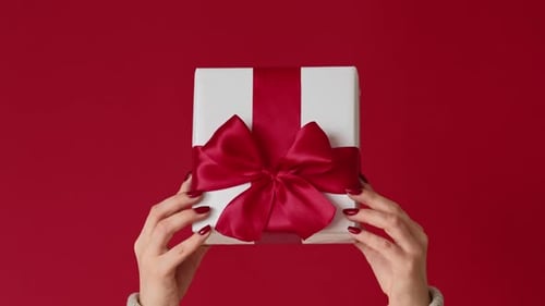 Hands Holding White Gift Box with Red Ribbon