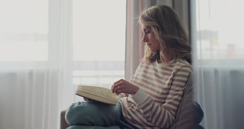 Attractive Woman Reading Book While Sitting on a Sofa at Home