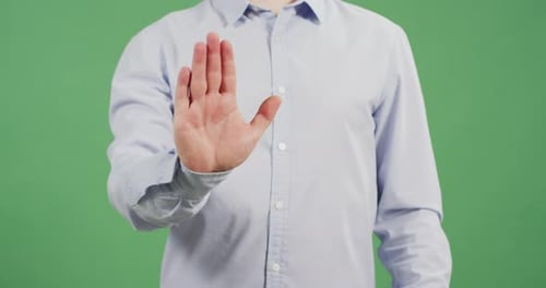 Adult Gives Stop Gesture Against Green Background
