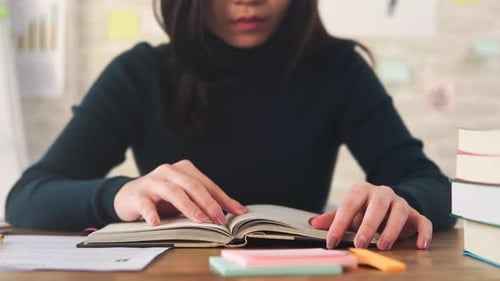 Jeune étudiante asiatique se concentrant sur la lecture d'un livre à la table