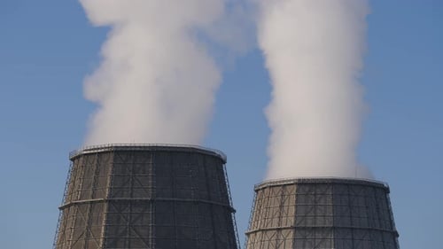 Cooling Towers Releasing Steam Against Blue Sky