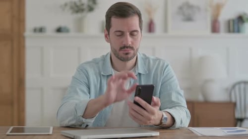 Junger Mann benutzt Smartphone im Büro