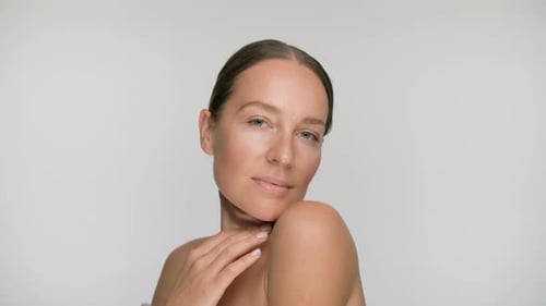 Close-up Beauty Portrait of Young Woman with Smooth Healthy Skin, She Gently Touches Her Shoulders