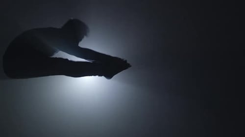 Silhouetted Athlete Performs Tricking Jump in Dark