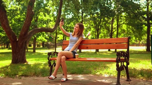 Woman Sitting on Park Bench Taking Selfie