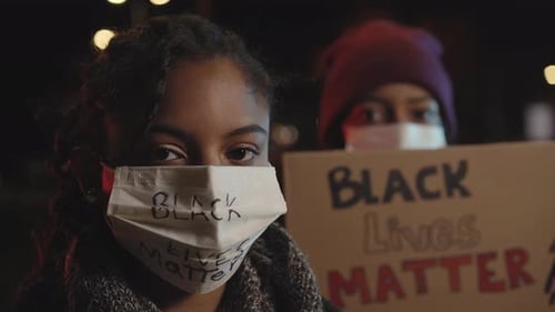 People at Night Protesting with Signs and Masks