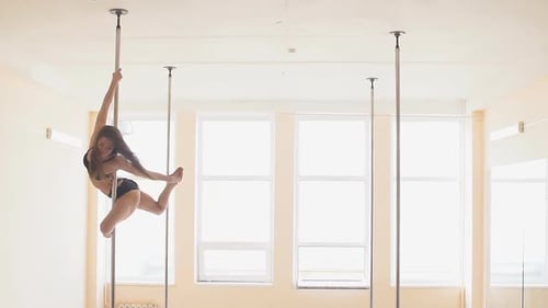 Attractive Woman Performing Pole Dance in Bright Studio