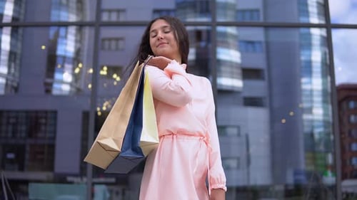 Fille dans une robe après le shopping avec des sacs à la main