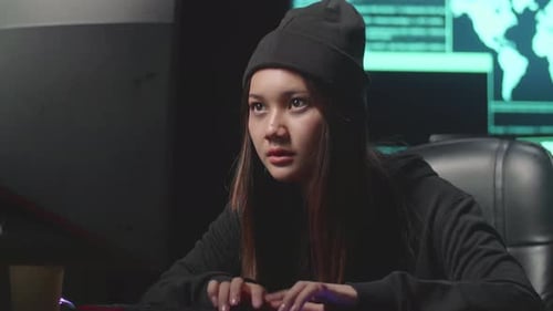 Jeune femme asiatique hacker utilisant le piratage informatique, code sur plusieurs écrans d'ordinateur