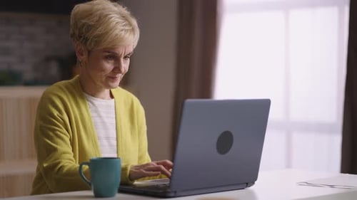 Woman Working on Laptop at Home Drinking Coffee