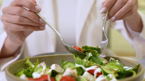 Woman Mixing Salad with Two Forks Close Up