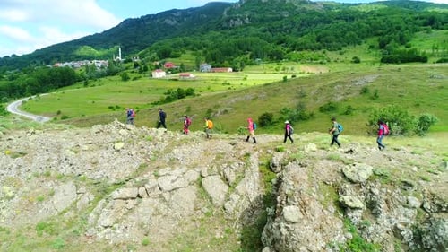 Hikers Traverse Rocky Hillside in Rural Landscape