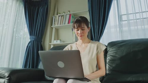 Asian Happy business woman office worker use laptop computer work from home in living room.